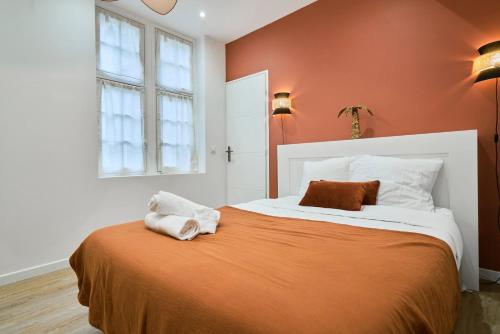 a bedroom with a large bed with orange walls at Appartement Central et Tout Equipé - 2 - Mon Groom in Troyes
