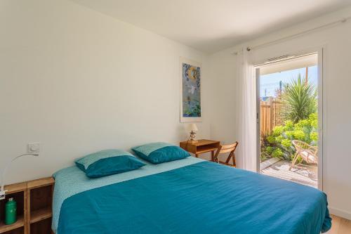 - une chambre avec un lit bleu et une porte coulissante en verre dans l'établissement ETXETXOA Appartement lumineux avec jardin au cœur de Chiberta, à Anglet