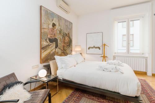 a white bedroom with a large painting on the wall at Youhosty - Brera 17 in Milan