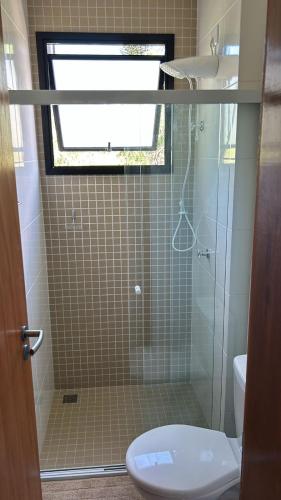 a bathroom with a shower with a toilet and a window at Pousada Bettys in Ubatuba