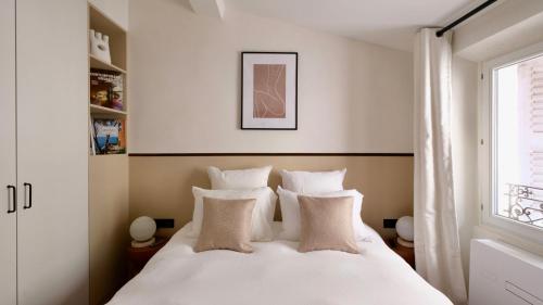 une chambre avec un lit blanc avec des oreillers et une fenêtre dans l'établissement Exceptional facing Palais Cannes 3, à Cannes