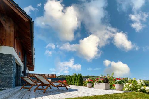 two chairs sitting on a deck with a cloudy sky at Penzion Stříbrník in Krásná
