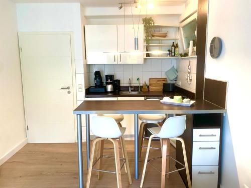 a kitchen with a counter with white stools at Meeresrauschen - Strandnah und ruhig in Scharbeutz