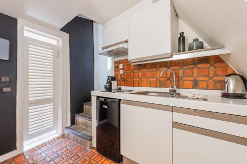 une cuisine avec des armoires blanches et un évier dans l'établissement Le Cosy Stras - Studio climatisé, à Strasbourg