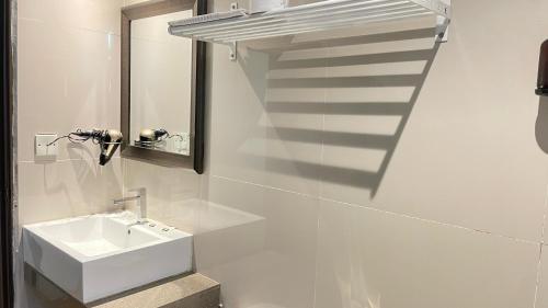 a white bathroom with a sink and a staircase at The Riverbank Hotel By MRVJ Business in Kuantan