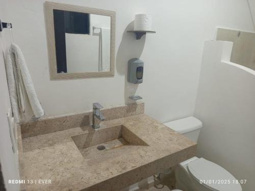 a bathroom with a sink with a mirror and a toilet at Quinta YaaxBe in Homún