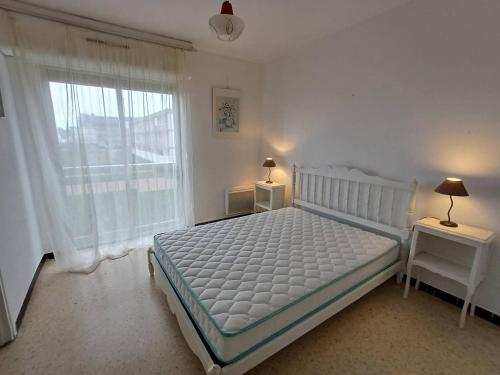 une chambre avec un lit blanc et une grande fenêtre dans l'établissement F2 à Balaruc-les-Bains avec vue sur l'étang, proche Thermal, 1 chambre, non-fumeur - FR-1-571-64, à Balaruc-les-Bains