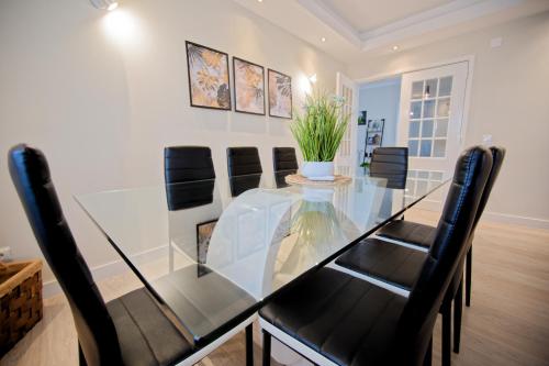 a dining room with a glass table and black chairs at Villa As Cumadres in Azeitao