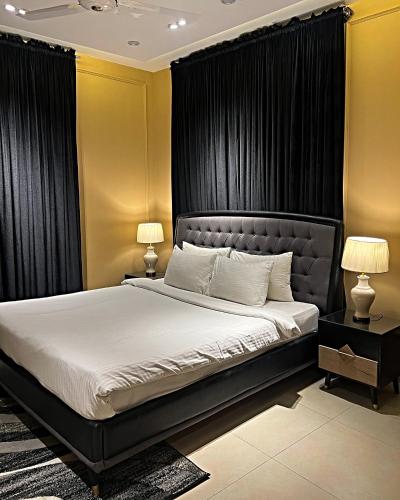 a bedroom with a large bed with black curtains at Central City 2BHK by StayMehman in Rawalpindi