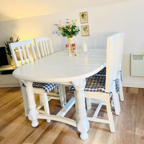 a white table and chairs with a vase of flowers at Idyllisk sommerhus tæt ved Blåvand in Billum