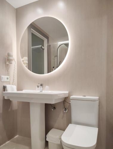 a bathroom with a sink and a mirror and a toilet at Hotel Oasis Plaza in Benidorm