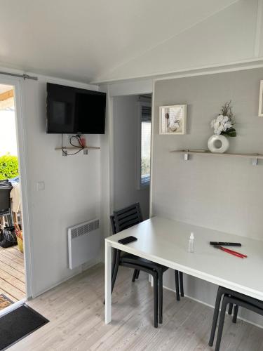 Il comprend un salon doté d'une table blanche et d'une télévision. dans l'établissement Mobile home 4-6 places Camping les sables du midi Valras, à Sérignan