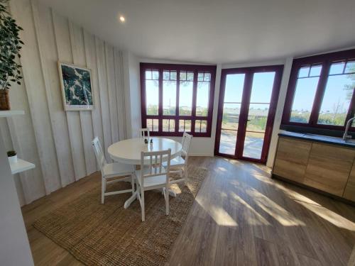 une salle à manger avec une table, des chaises et des fenêtres dans l'établissement Maison Première ligne Andernos, à Andernos-les-Bains