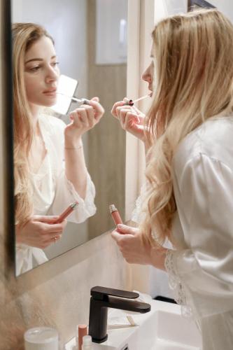 a woman brushing her teeth in front of a mirror at Il Vico del Greco B&B in Le Castella