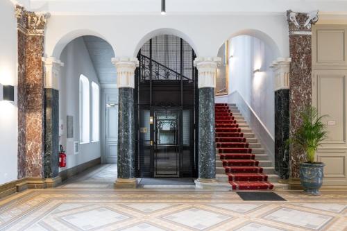 una escalera en un edificio con escaleras rojas y pilares en Coquette Suite au Bernascon Appartement 2 étoiles avec avec vue Lac, en Aix-les-Bains