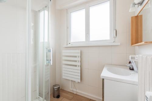 une salle de bain blanche avec un lavabo et une douche dans l'établissement Berne, à Strasbourg