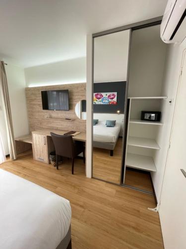 a hotel room with a desk and a bedroom at Hôtel Le Mas del Pechs - Chambres avec terrasse in Sarlat-la-Canéda