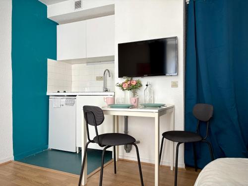 a small kitchen with a table and two chairs at La Bonbonnière Centre ville - Thermes - Netflix in Mont-Dore