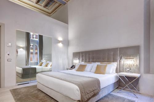 a bedroom with a large white bed and a mirror at Terrace Pantheon Relais in Rome