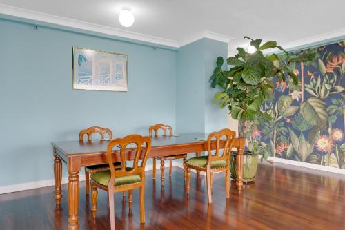 a dining room table with four chairs and a plant at Stylish 1BR Beachside Escape - Heart of Gold Coast in Gold Coast