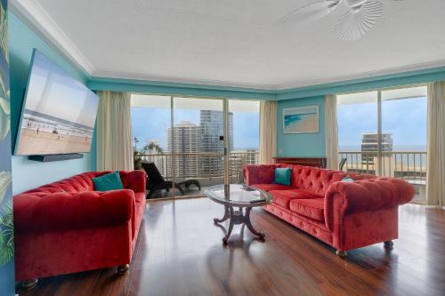 a living room with two red couches and a table at Stylish 1BR Beachside Escape - Heart of Gold Coast in Gold Coast