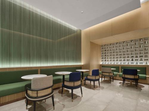 a waiting area with tables and chairs in a restaurant at Hilton Garden Inn Chengdu Tianfu Panda Tower in Chengdu