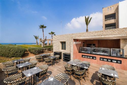 a patio with tables and chairs and the ocean at Hotel Riu Palace Tikida Agadir - All Inclusive in Agadir