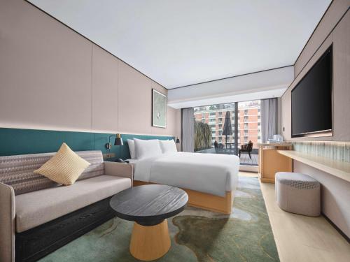 a hotel room with a bed and a couch at Hilton Garden Inn Chengdu Tianfu Panda Tower in Chengdu