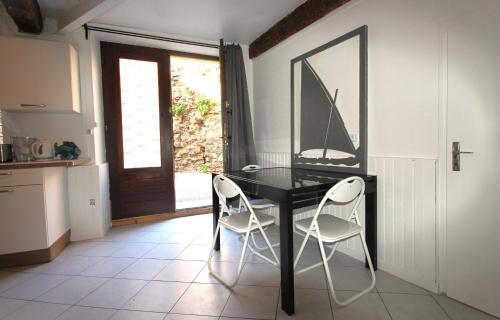 une salle à manger avec une table noire et deux chaises blanches dans l'établissement Égalité, à Collioure