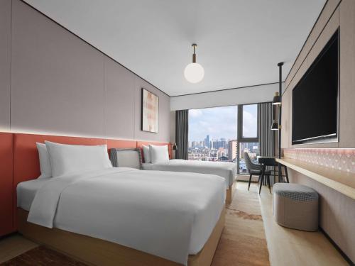 two beds in a hotel room with a large window at Hilton Garden Inn Chengdu Tianfu Panda Tower in Chengdu