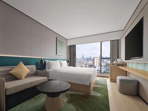 a hotel room with a bed and a couch and a tv at Hilton Garden Inn Chengdu Tianfu Panda Tower in Chengdu