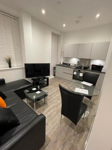 a living room with a black couch and a table at 1 bed apartment in the heart of Staines town centre in Staines upon Thames