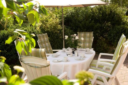 a white table with chairs and an umbrella at Haus Heide "unten" in Borkum