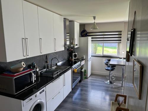 une cuisine avec des armoires blanches et un évier dans l'établissement Zénith Stade Parc Expo Palais des Sports, Apt 2ch 4pers parking, à Caen