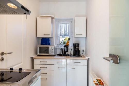 a kitchen with white cabinets and a microwave at Ferienwohnung bei Will in Stützerbach