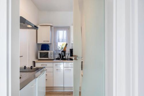 a kitchen with white cabinets and a microwave at Ferienwohnung bei Will in Stützerbach
