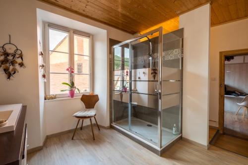 - une douche en verre dans une chambre avec une chaise dans l'établissement Meublé de tourisme 4 étoiles, Centre historique, à Kaysersberg