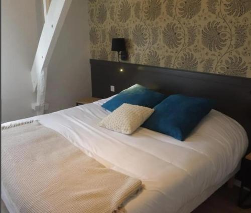 un lit blanc avec des oreillers bleus dans une chambre dans l'établissement Relais du méne, à Collinée