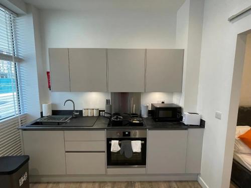 a kitchen with white cabinets and a stove top oven at 1 bed apartment in the heart of Staines town centre in Staines upon Thames