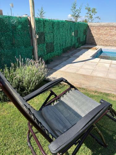 una silla sentada en el césped junto a una piscina en CABAÑA Los abuelos, en Ciudad Lujan de Cuyo