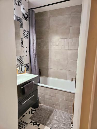 une salle de bain avec une baignoire et un lavabo dans l'établissement Appart Cosy Bordeaux centre, à Bordeaux