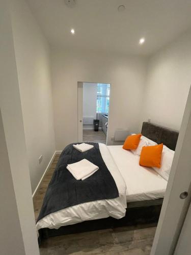 a bedroom with a large bed with orange pillows at 1 bed apartment in the heart of Staines town centre in Staines upon Thames