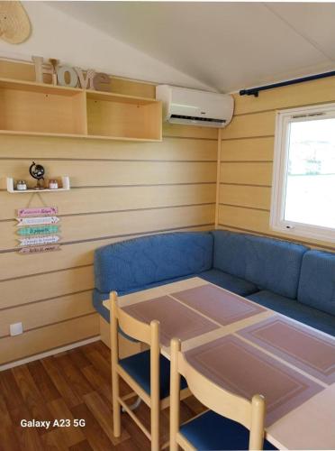 un salon avec un canapé bleu et une table dans l'établissement Mobil Home Loulousab10, à Port-la-Nouvelle