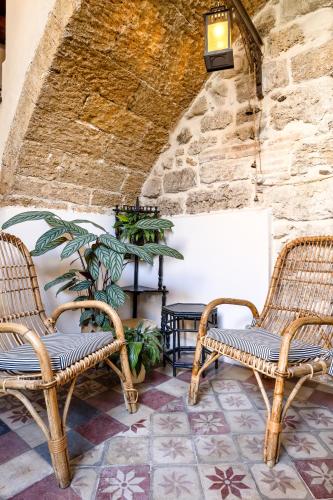 two wicker chairs sitting next to a stone wall at Sette Fate Suites & Spa in Palermo