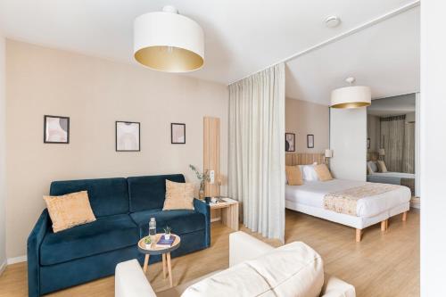 a living room with a blue couch and a bed at Appart hôtel Q7 Lodge Lyon 7 in Lyon