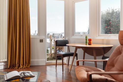 a living room with a table and chairs and windows at Chelsea House Holiday Apartments in Falmouth