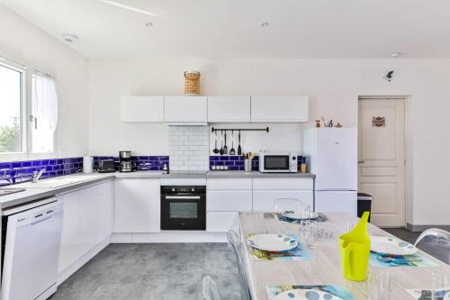 une cuisine avec des placards blancs et une table avec une salle à manger dans l'établissement Le Gois - Terrasse - Parking, à Beauvoir-sur-Mer