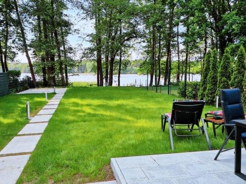 a lawn with two chairs and a table in the grass at Haus Wentowseeblick in Zehdenick