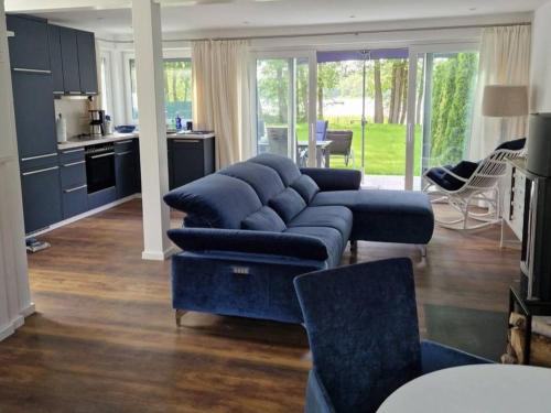 a living room with a blue couch and a kitchen at Haus Wentowseeblick in Zehdenick