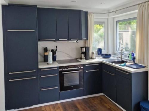 a kitchen with navy blue cabinets and a window at Haus Wentowseeblick in Zehdenick